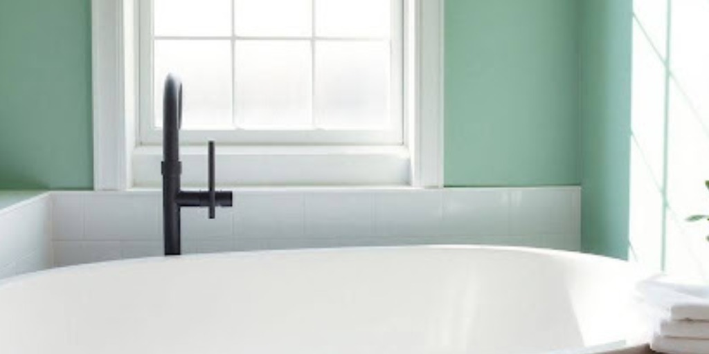 white reglazed bathtub against mint green wall with black fixtures